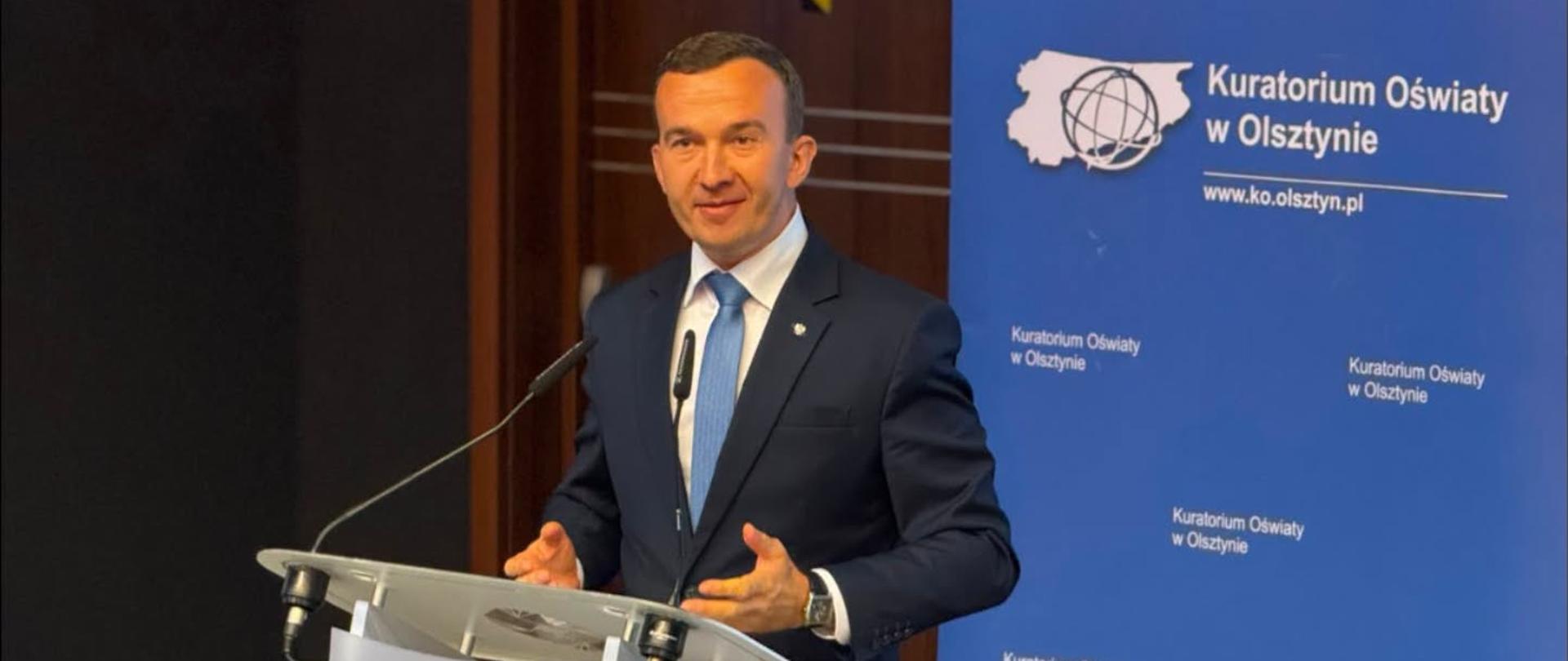 Mężczyzna stoi przy mównicy 