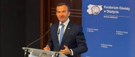 Mężczyzna stoi przy mównicy 
