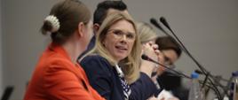 Na zdjęciu wiceminister Monika Sikora siedzi za stołem konferencyjnym w towarzystwie innych uczestników