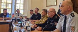 Przedstawiciele służb ratowniczych z Polski, Niemiec i Czech podczas spotkania przy stole konferencyjnym w ratuszu w Żytawie. Uczestnicy omawiają doświadczenia i dobre praktyki w zakresie transgranicznej współpracy w dziedzinie ochrony przeciwpożarowej i ochrony przed klęskami żywiołowymi.