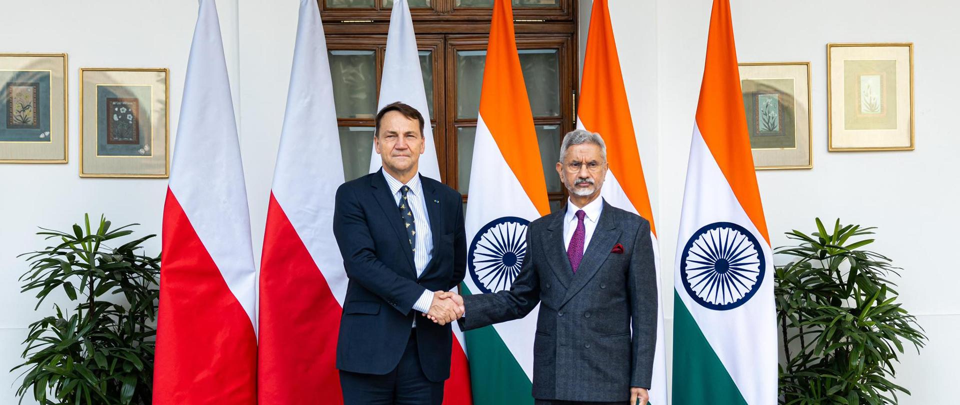 Deputy Prime Minister Radosław Sikorski shakes hands with Minister for External Affairs of India Dr. S. Jaishankar at Hyderabad House, standing behind a row of Polish and Indian flags.