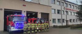 Strażacy stoją przed samochodami gaśniczymi, oddając hołd ofiarom katastrofy smoleńskiej. W tle jest jednostka ratowniczo-gaśnicza.