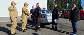 Zdjęcie przedstawia moment przekazania samochodu operacyjnego z Komendy Powiatowej PSP w Lubinie do OSP Chobienia. Przekazanie odbywa się na placu wewnętrznym Komendy Powiatowej PSP w Lubinie.