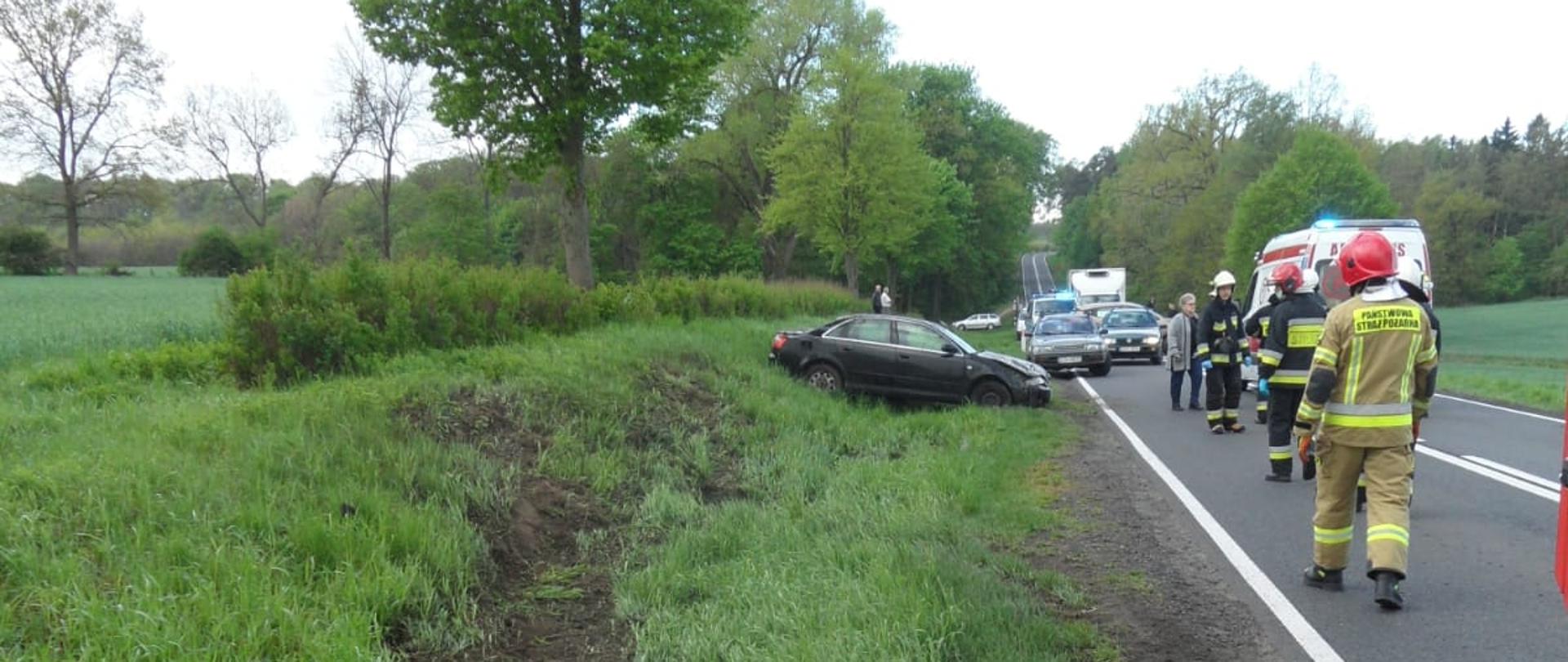 "Przeorane" pobocze drogi, na którym stoi rozbite audi, na drodze strażacy