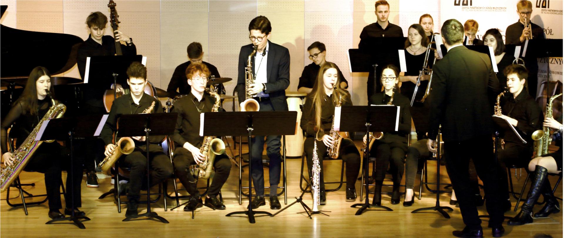 Grafika przedstawia osoby muzykujące w Big Bandzie