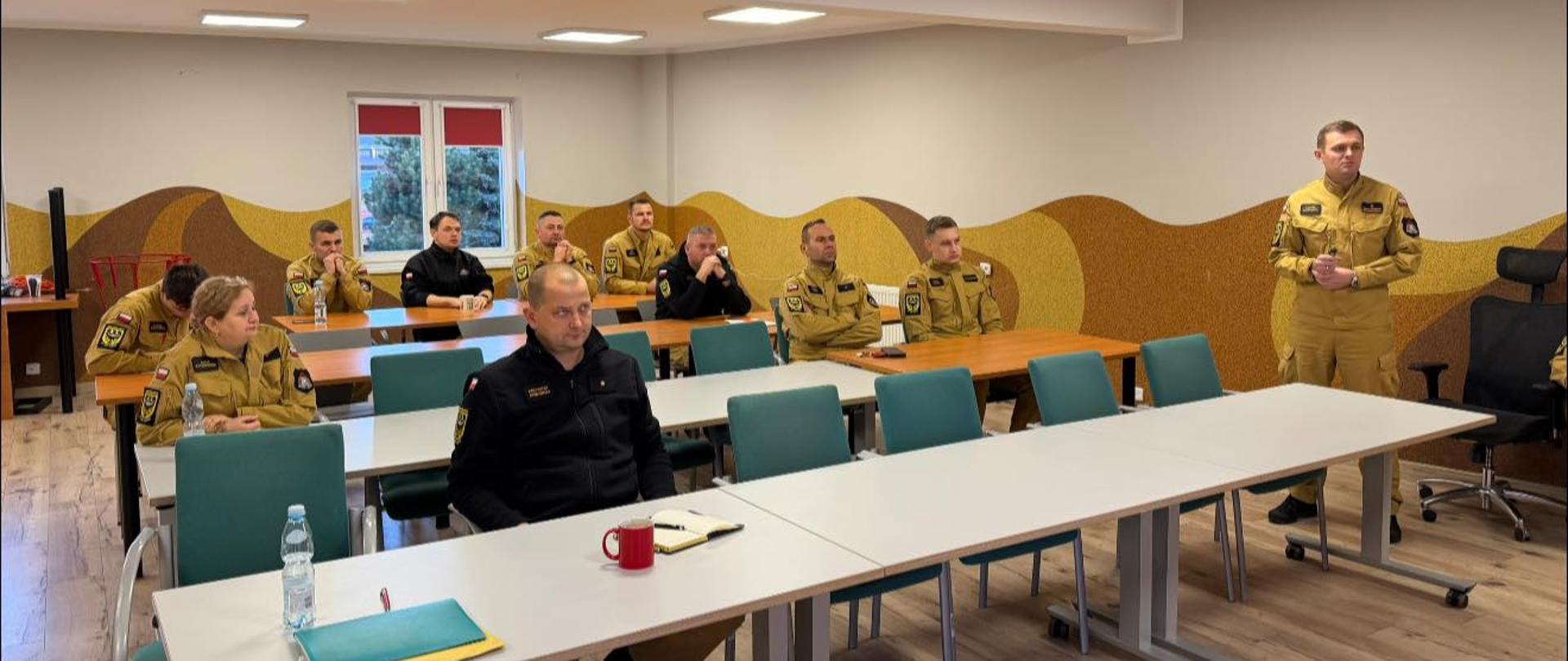 Obsada stanowiska kierowania oraz dowódcy zmian siedzą na auli podczas odprawy służbowej