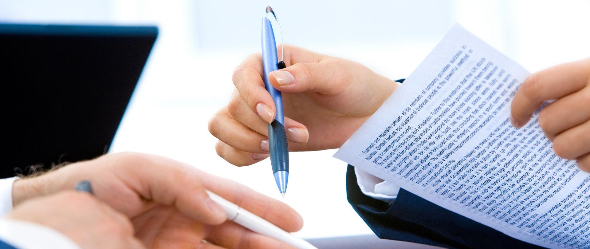 zdjęcie rąk osób wypełniających dokumenty.