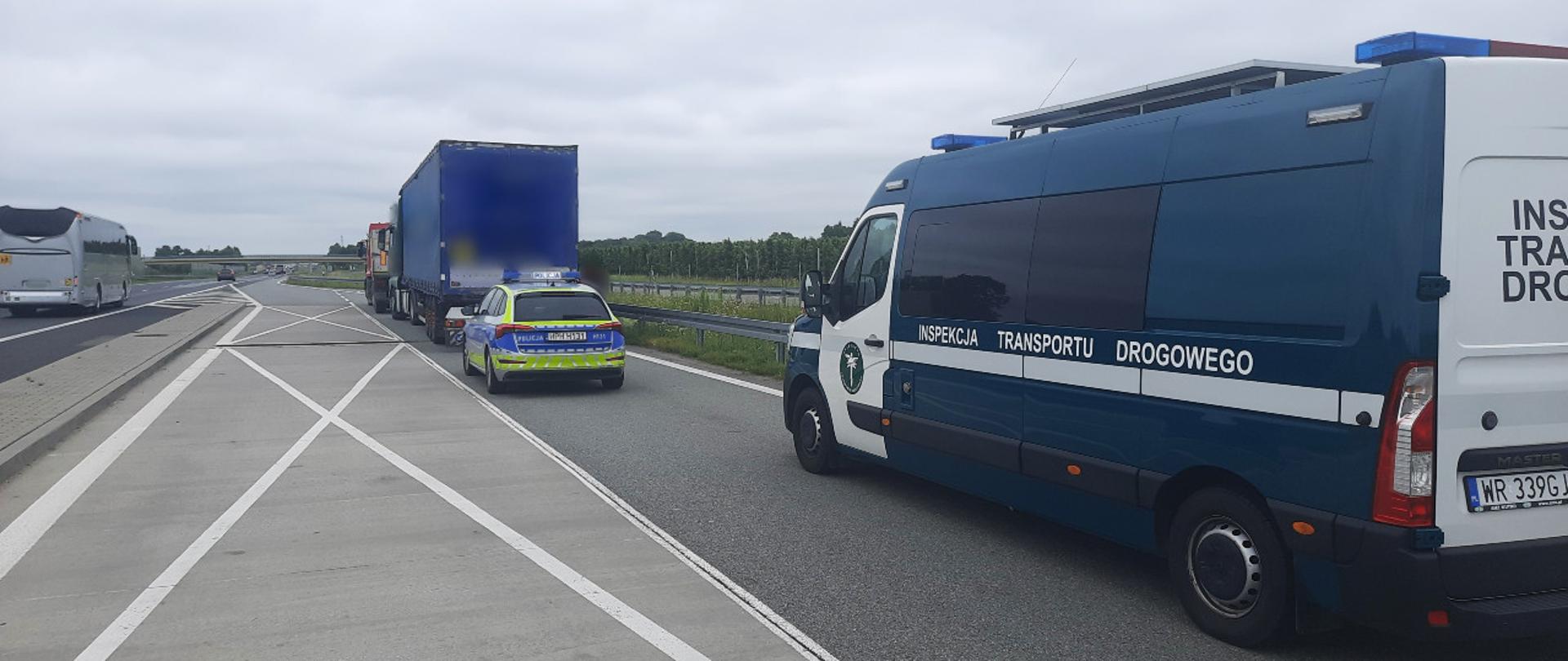 Na pierwszym planie (od prawej): oznakowany furgon mazowieckiej Inspekcji Transportu Drogowego stoi w zatoce kontrolnej przy ekspresowej „siódemce” pod Grójcem. W tle: oznakowany radiowóz grójeckiej Policji. Przed radiowozem stoją dwie zatrzymane do kontroli ciężarówki.