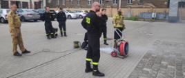 Na zdjęciu strażacy sprawdzają kształt strumienia powietrza przy pomocy zadymiarki