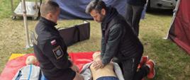 Strażak z KP PSP Kozienice pokazuje jak w prawidłowy sposób wykonywać uciśnięcia klatki piersiowej