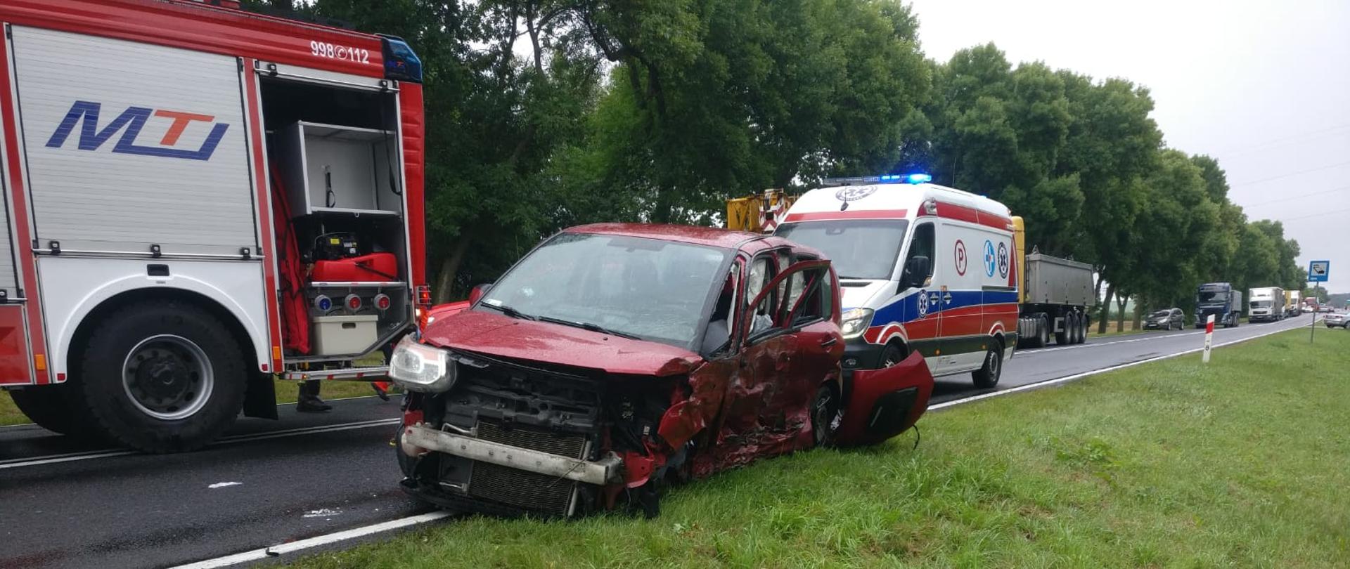 Zdjęcie przedstawia samochód osobowy uczestniczący w wypadku komunikacyjnym, który znajduje się na pasie drogowym. Samochód posiada uszkodzenie przodu oraz lewego boku.
