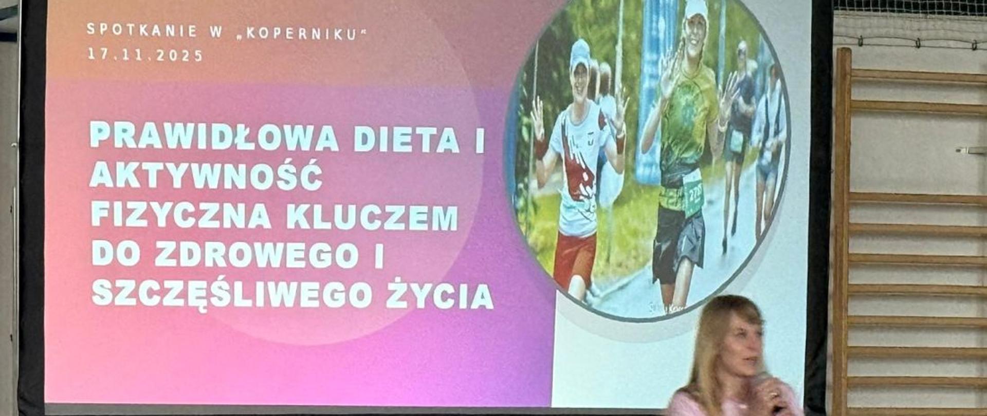 Przed ekranem, na którym wyświetlono slajd prezentacji, stoi kobieta prowadząca wykład, mówi do mikrofonu