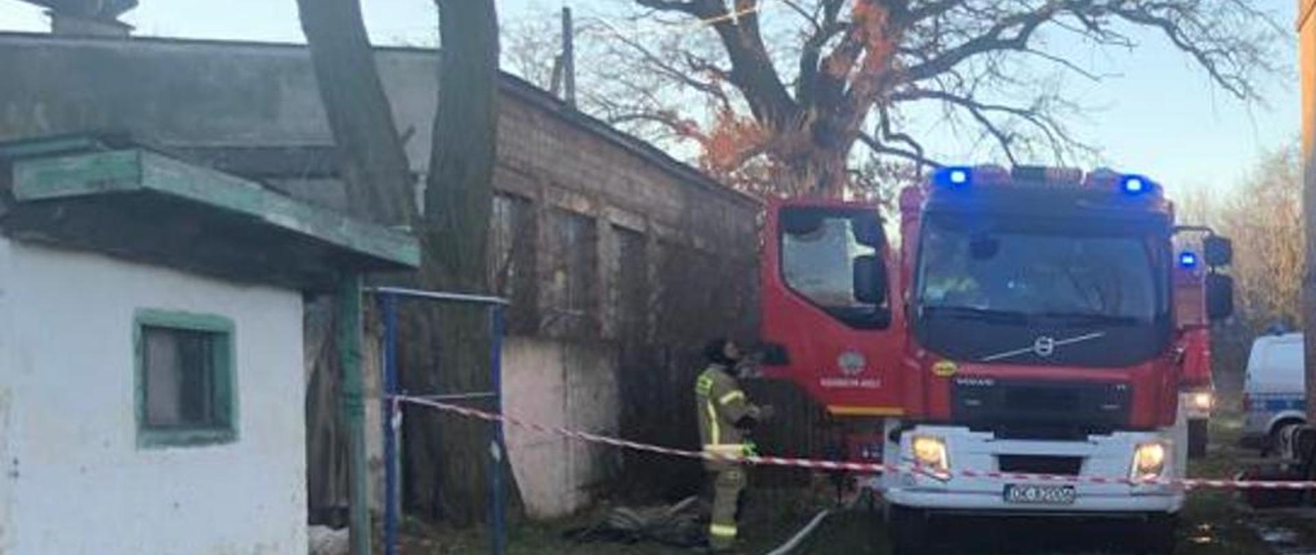 Samochód straży pożarnej stoi obok budynku z cegły