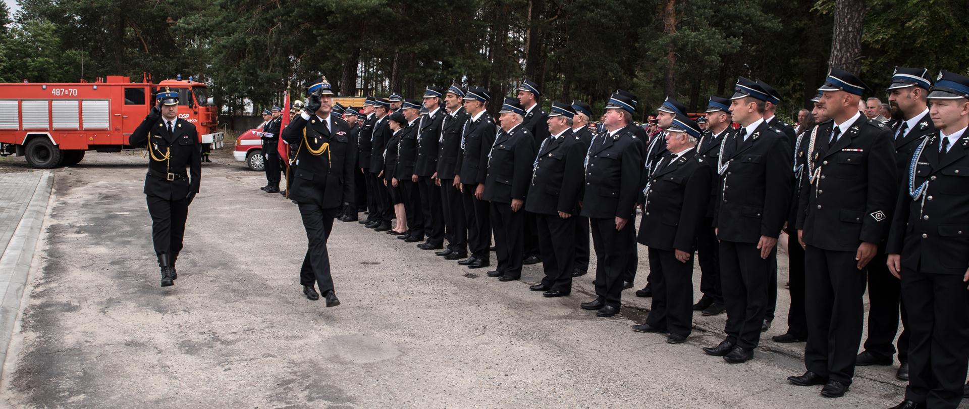 Zdjęcie przedstawia Zastępcę Podkarpackiego Komendanta Wojewódzkiego st. bryg. Janusza Jabłońskiego podczas przeglądu pododdziałów na uroczystości otwarcia nowej remizy OSP Narol. Z prawej strony widoczny pododdział druhów ochotników z trenu gminy Narol.