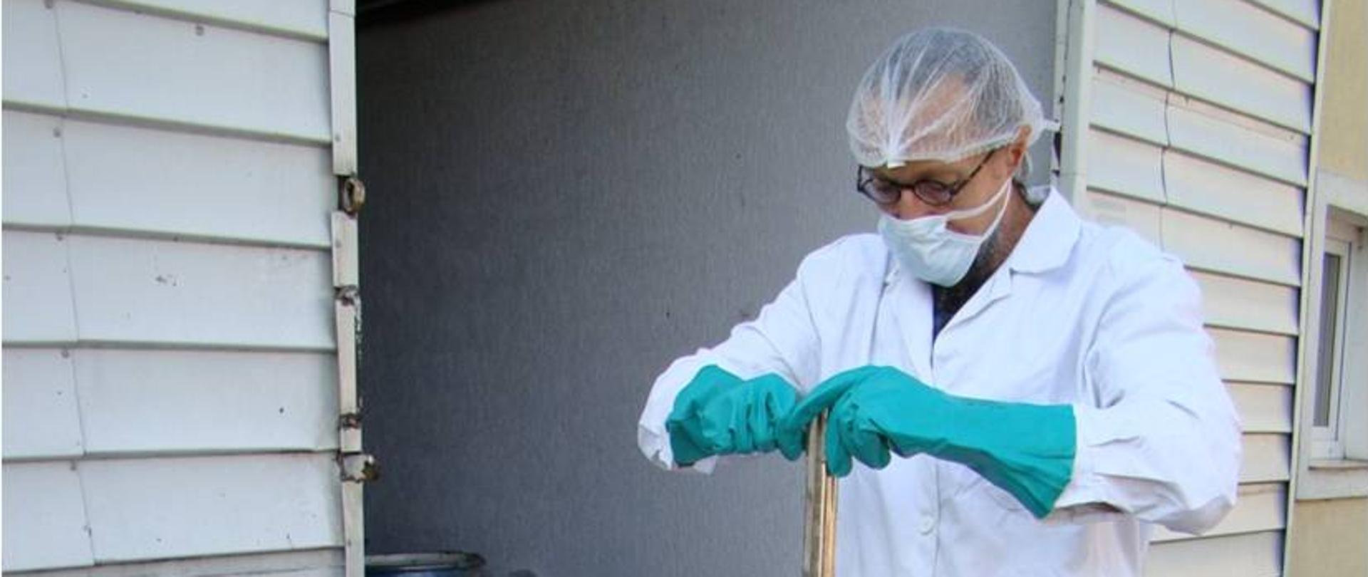 Inspektor w odzieży ochronnej pobiera próbkę artykułu z beczki