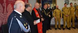 Zdjęcie przedstawia ks. prałata Mieczysława Rusina kapelana strażaków Archidiecezji Przemyskiej i ks. dr Mariana Hofmana kapelana strażaków powiatu przemyskiego oraz komendanta miejskiego PSP wraz zastępcą i zaproszonymi gośćmi podczas modlitwy wigilijnej