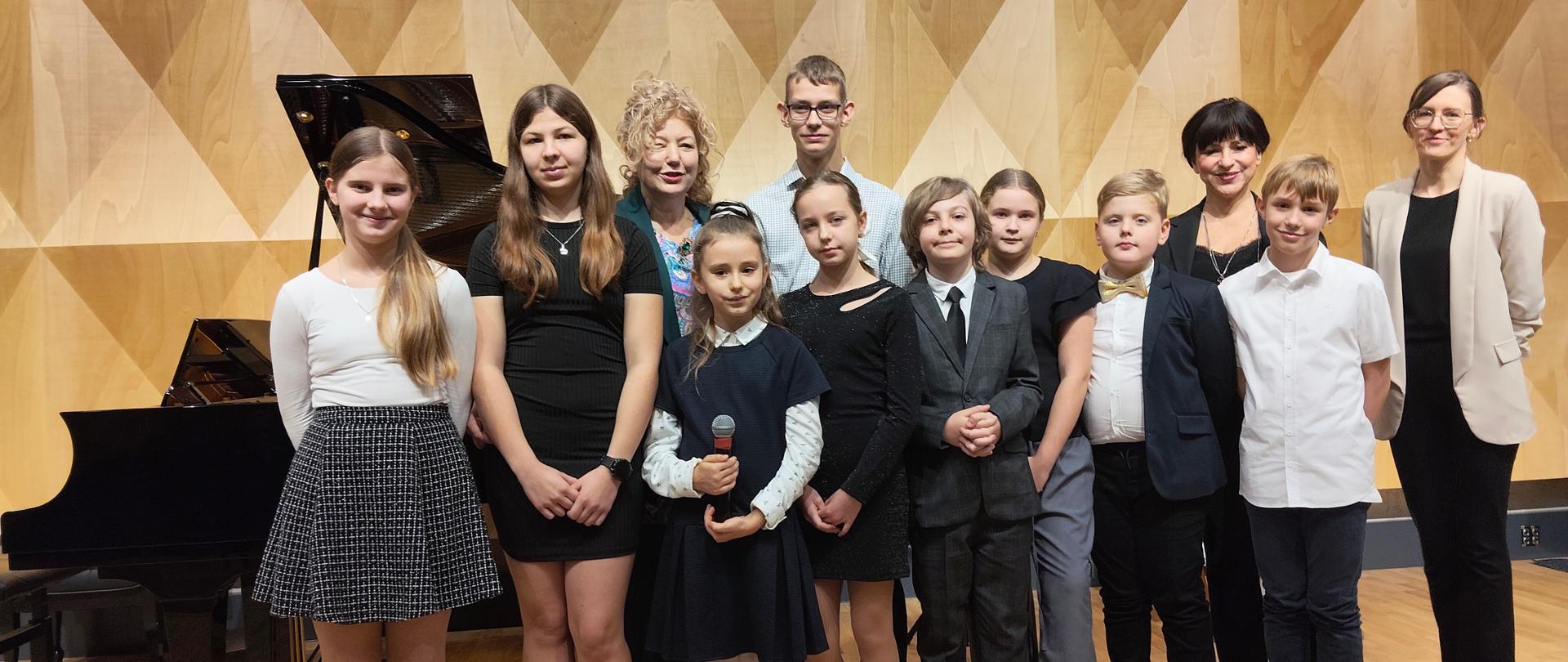 Grupa uczniów na scenie szkoły muzycznej