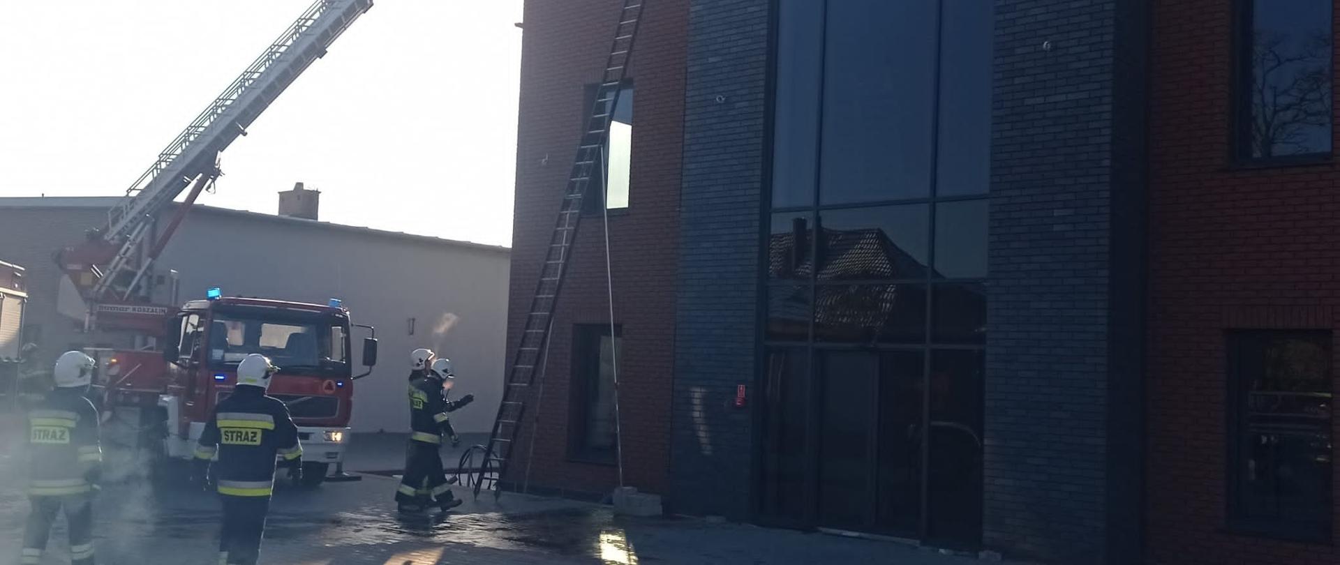 samochód strażacki, budynek biurowy, kostka brukowa strażacy