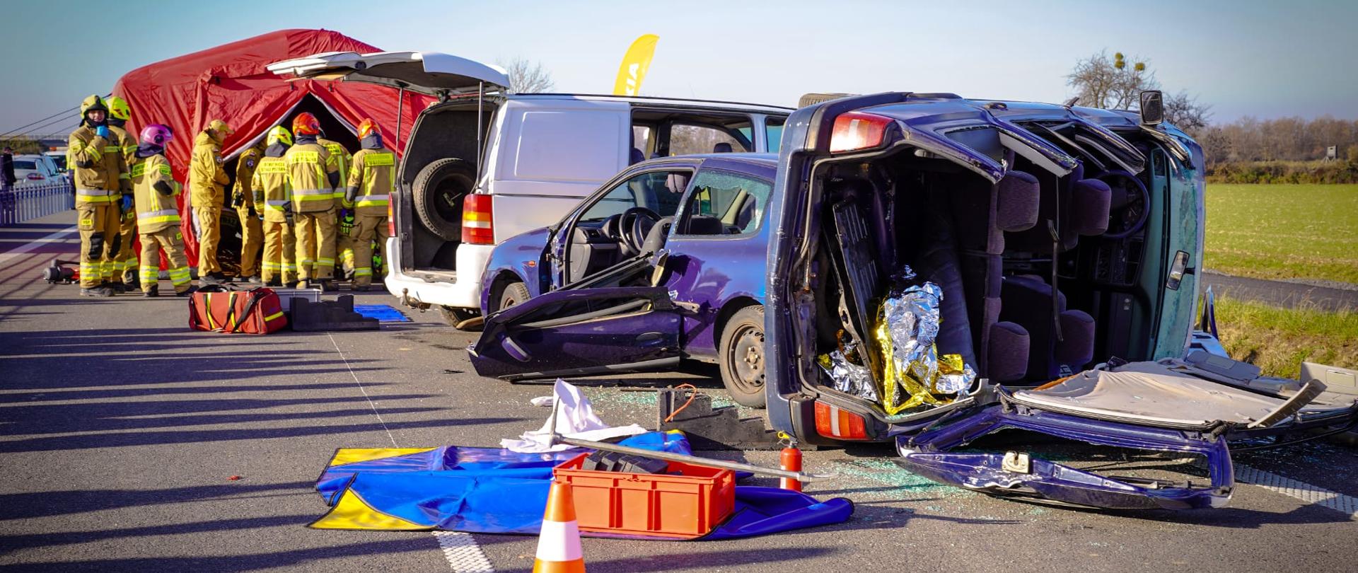 Zdjęcie przedstawia uszkodzone pojazdy oraz rozstawiony namiot. 