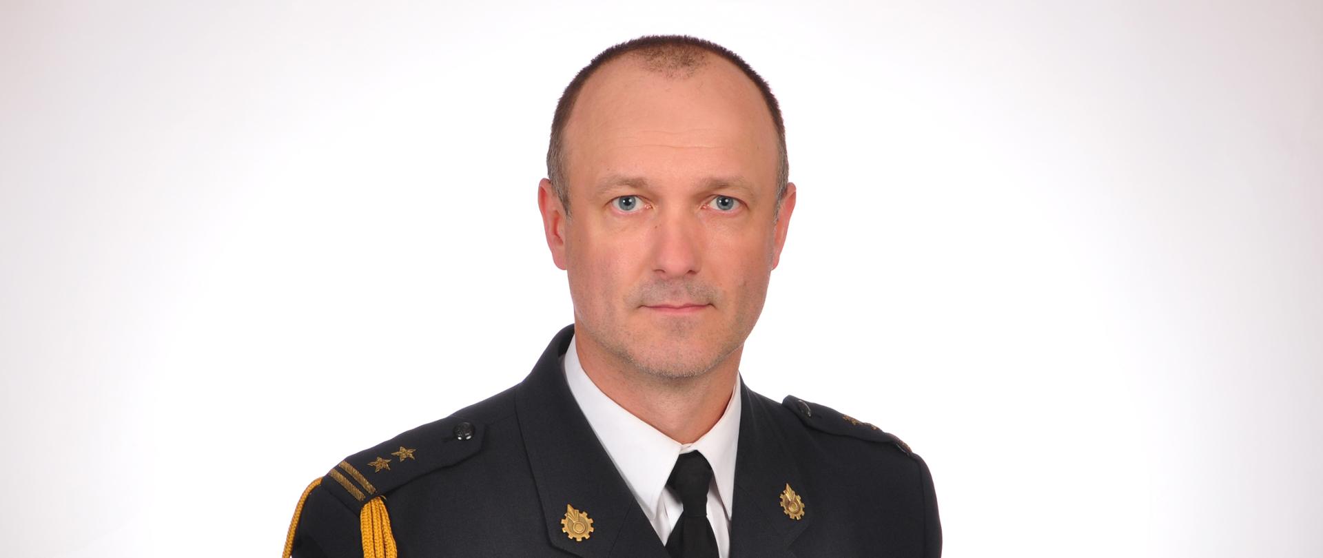 Zdjęcie portretowe bryg. mgr inż. Pawła Kowalskiego - Zastępcy Komendanta Powiatowego PSP w Kozienicach w mundurze wyjściowym na jasnym tle