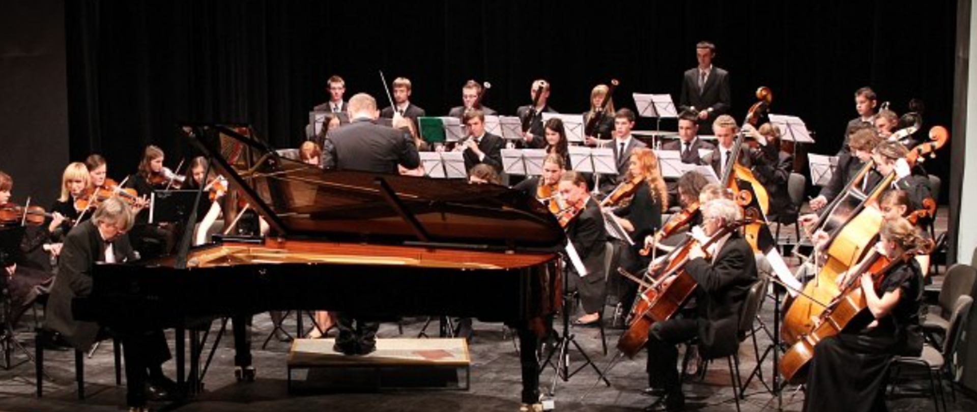 Zdjęcie przedstawia orkiestrę Państwowej Szkoły Muzycznej I i II st. im. Fryderyka Chopina w Nowym Sączu. Na środku widoczny solista - pianista.