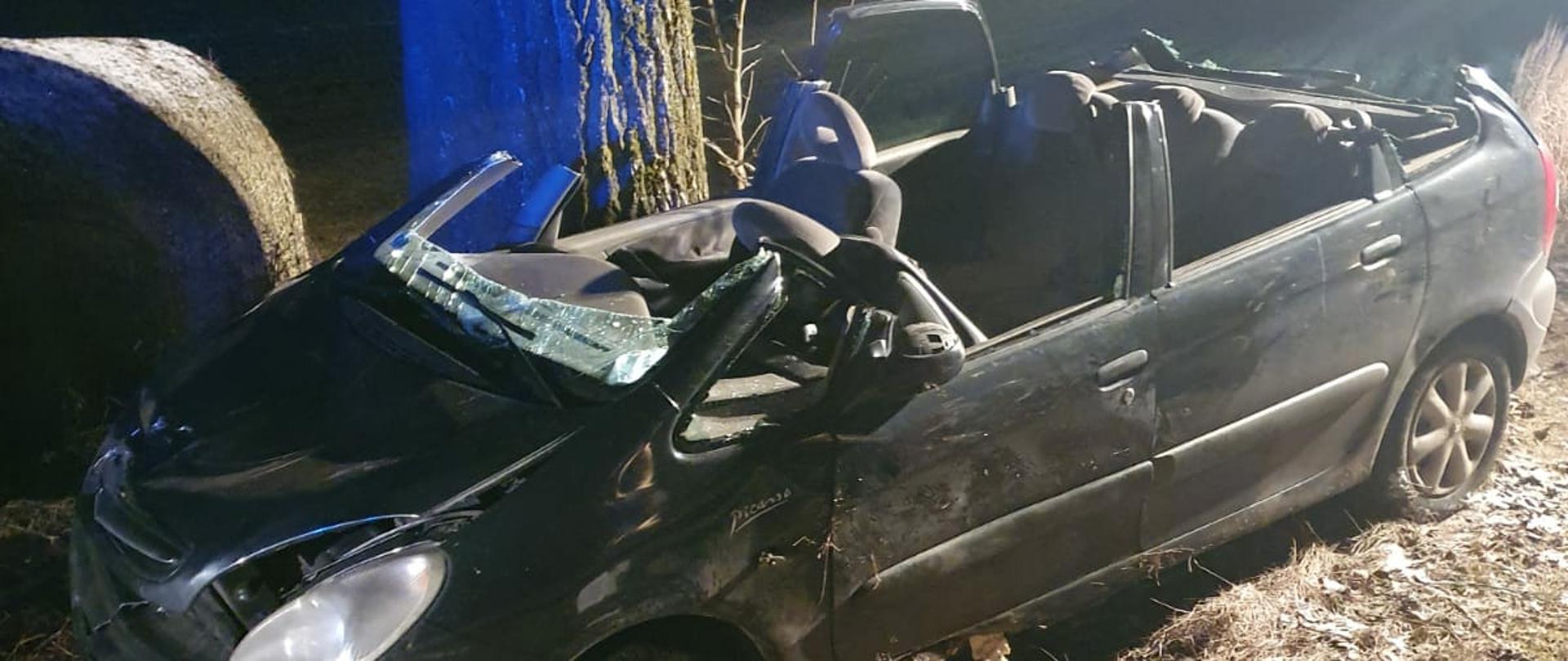 Zdjecie przedstawia samochód osobowy, który uderzył w drzewo. Samochód ma odcięty dach, który usunęli strażacy podczas ewakuacji osoby poszkodowanej.
