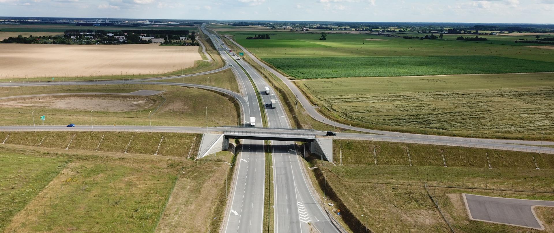 Dwujezdniowa droga ekspresowa w środku zdjęcia biegnie wśród pól aż po horyzont