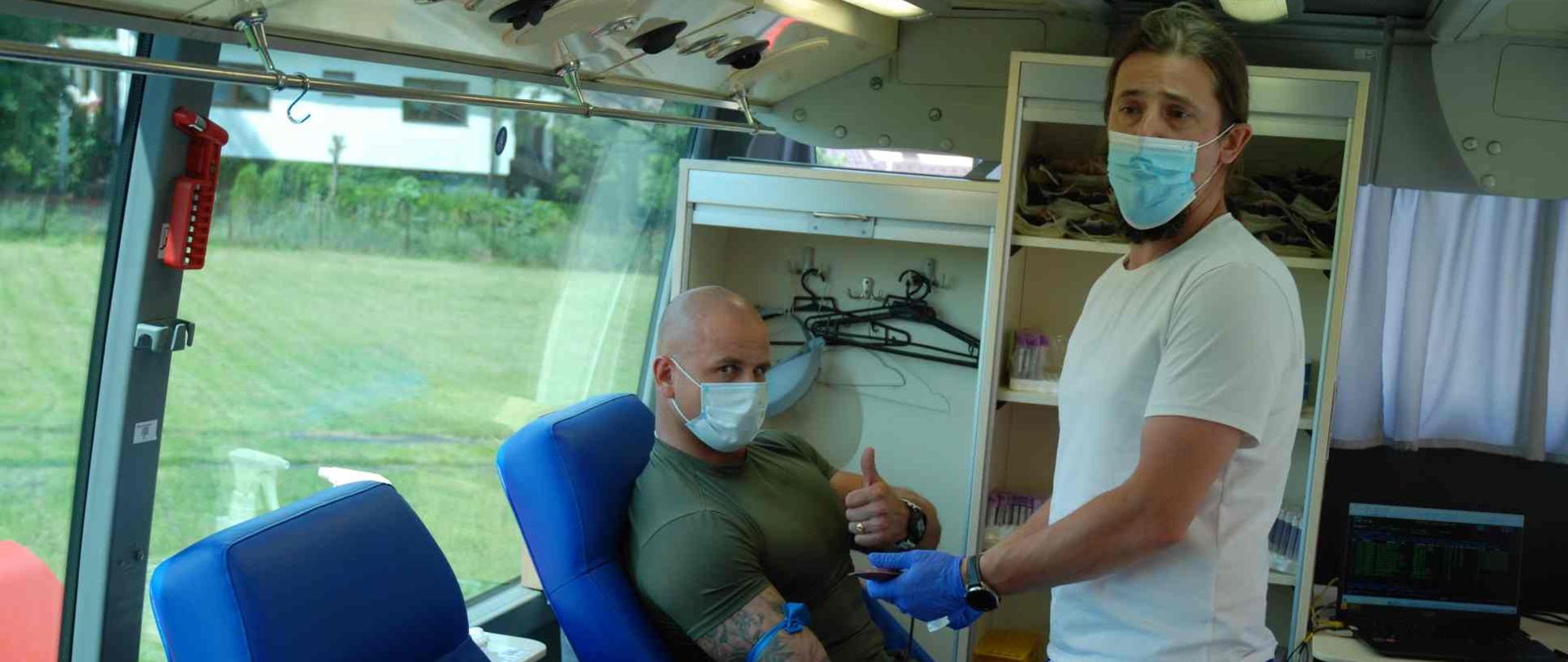 Chętni oddający krew wewnątrz krwiobusa.