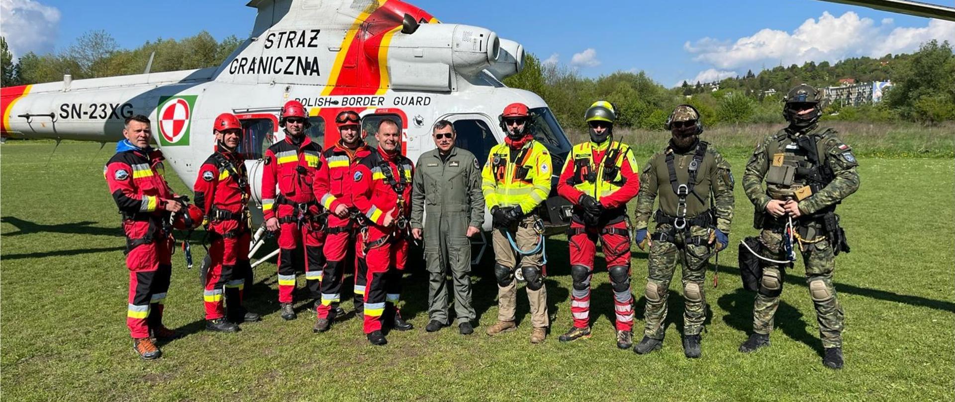 Pamiątkowe zdjęcie przedstawicieli Państwowej straży Pożarnej, Straży Granicznej, Wojska Polskiego oraz GOPR przed śmigłowcem PZL Kania.