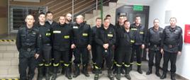 Na zdjęciu strażacy z Ochotniczych Straży Pożarnych po egzaminie kończącym szkolenie naczelników OSP. Strażacy ubrani w ubrania koszarowe koloru czarnego bez czapek na holu Komendy Powiatowej Państwowej Straży Pożarnej w Gorlicach.