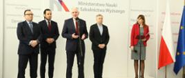 Minister Gowin i rektorzy uczelni stoją na tle ściany z logiem MNiSW