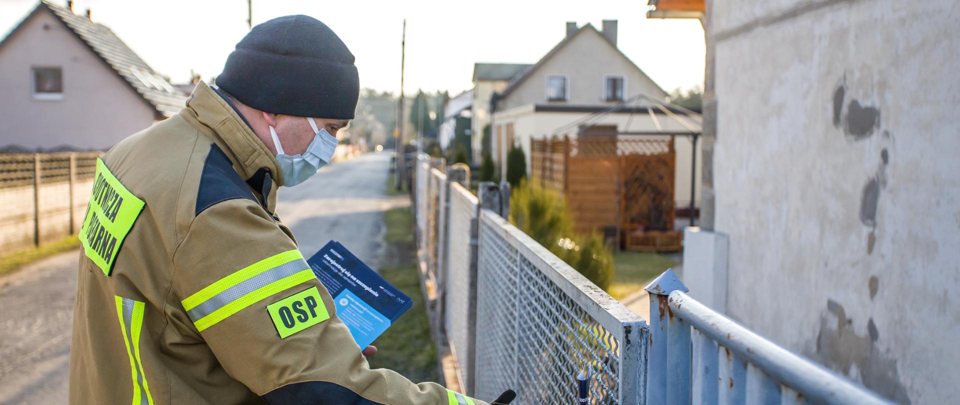 Strażak ochotnik dostarczający ulotki informacyjne w ramach akcji #Szczepimysię