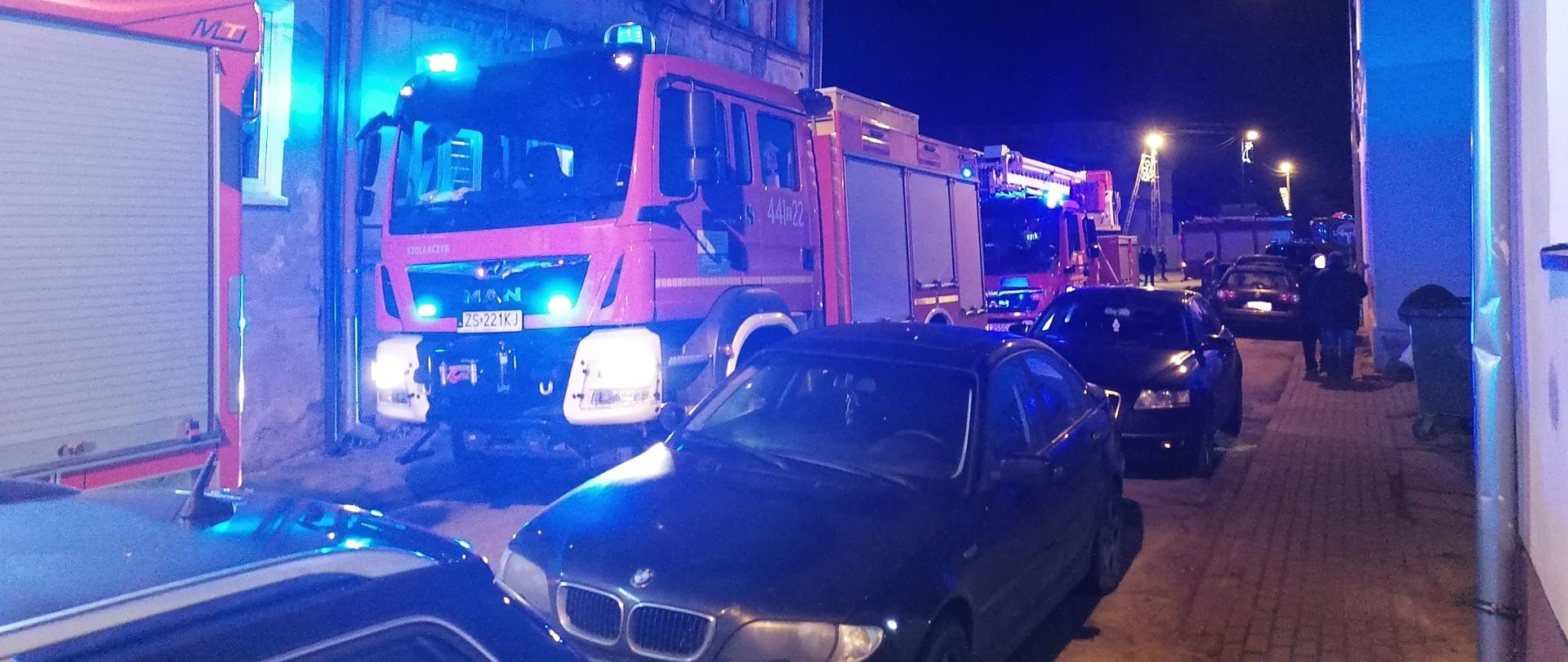 samochody gaśnicze na ulicy wśród zaparkowanych aut osobowych