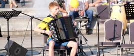 Zdjęcie przedstawia chłopaka grającego na akordeonie.