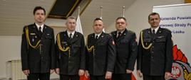 Zdjęcie przedstawia strażaków w mundurach wyjściowych Komendy Powiatowej Państwowej Straży Pożarnej w Lesku stojących w jednym szeregu.