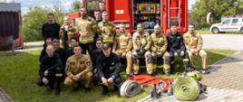Wspólne zdjęcie uczestników szkolenia i instruktorów., W tle widoczne samochody pożarnicze. Zdjęcie na poligonie ratowniczym Komendy Wojewódzkiej Państwowej Straży Pożarnej w Opolu. 