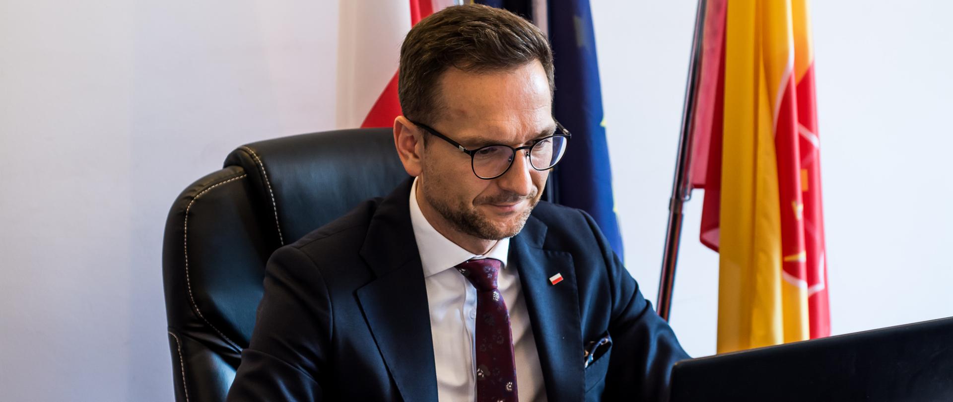 Wiceminister Waldemar Buda siedzi przed laptopem