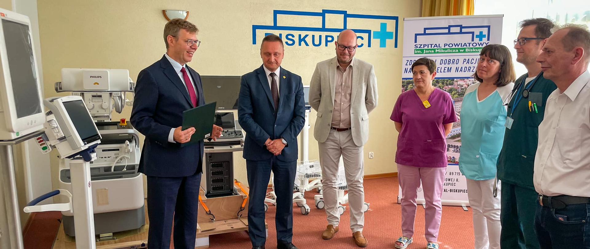 Wojewoda razem z lekarzami stoi uśmiechnięty 
