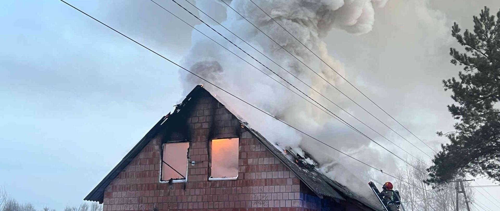 Zdjęcie. Pożar budynku. Uczestnicy akcji gaśniczej. 