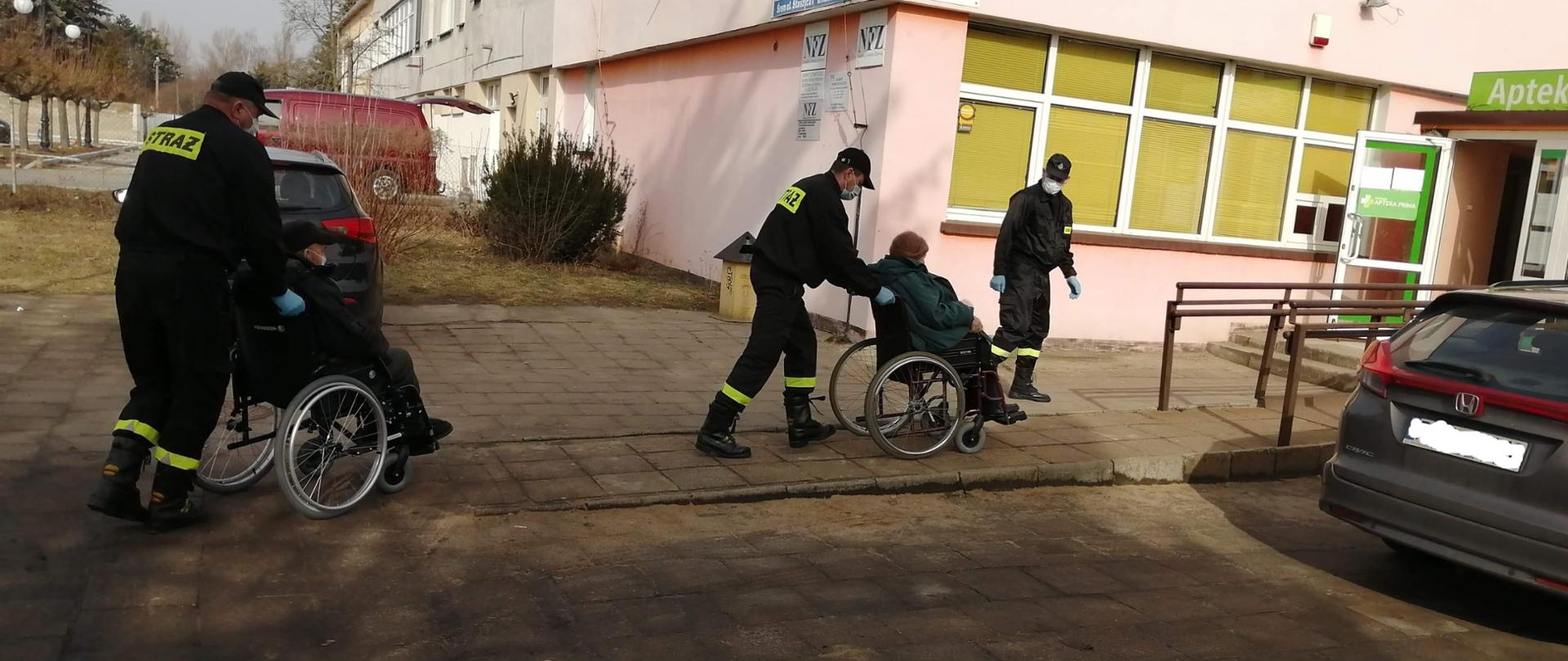 Na zdjęciu druhowie OSP transportujący do punktu szczepień seniorów na wózkach inwalidzkich