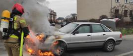 strażak gaszący auto osobowe