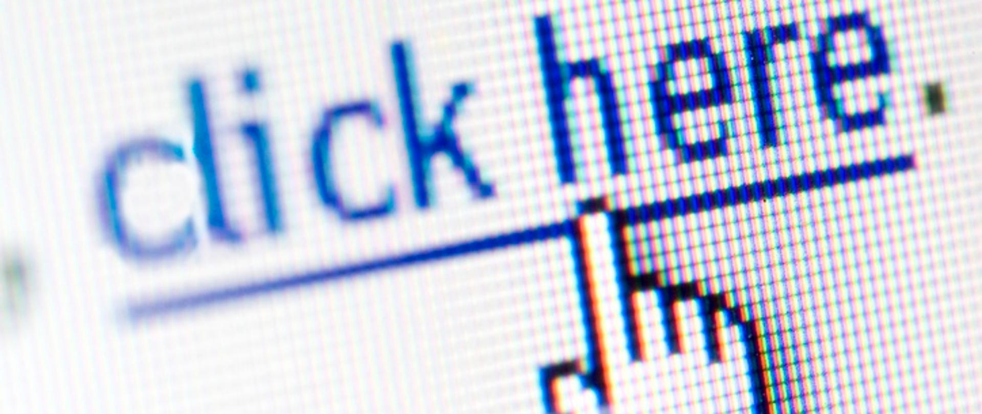 Białe tło z niebiskim, podkreślonym napisem: CLICK HERE. (Najedź myszą na link na ekranie komputera). Czarny kontur dłoni, który palcem wskazującym skierowany jest w stronę napisu. 