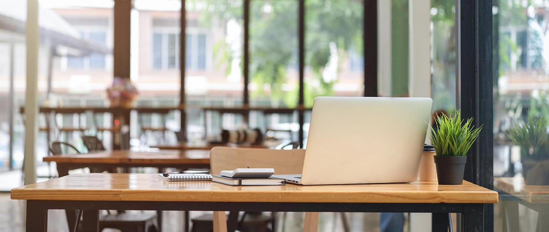 Photo of an office: a laptop and some papers on a desk.