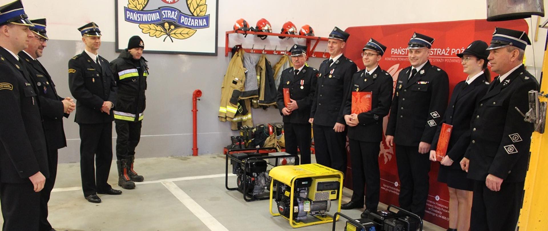 Zdjęcie przedstawia strażaków w trakcie uroczystego przekazania agregatów prądotwórczych.
W tle pomieszczenie garaży JRG.
