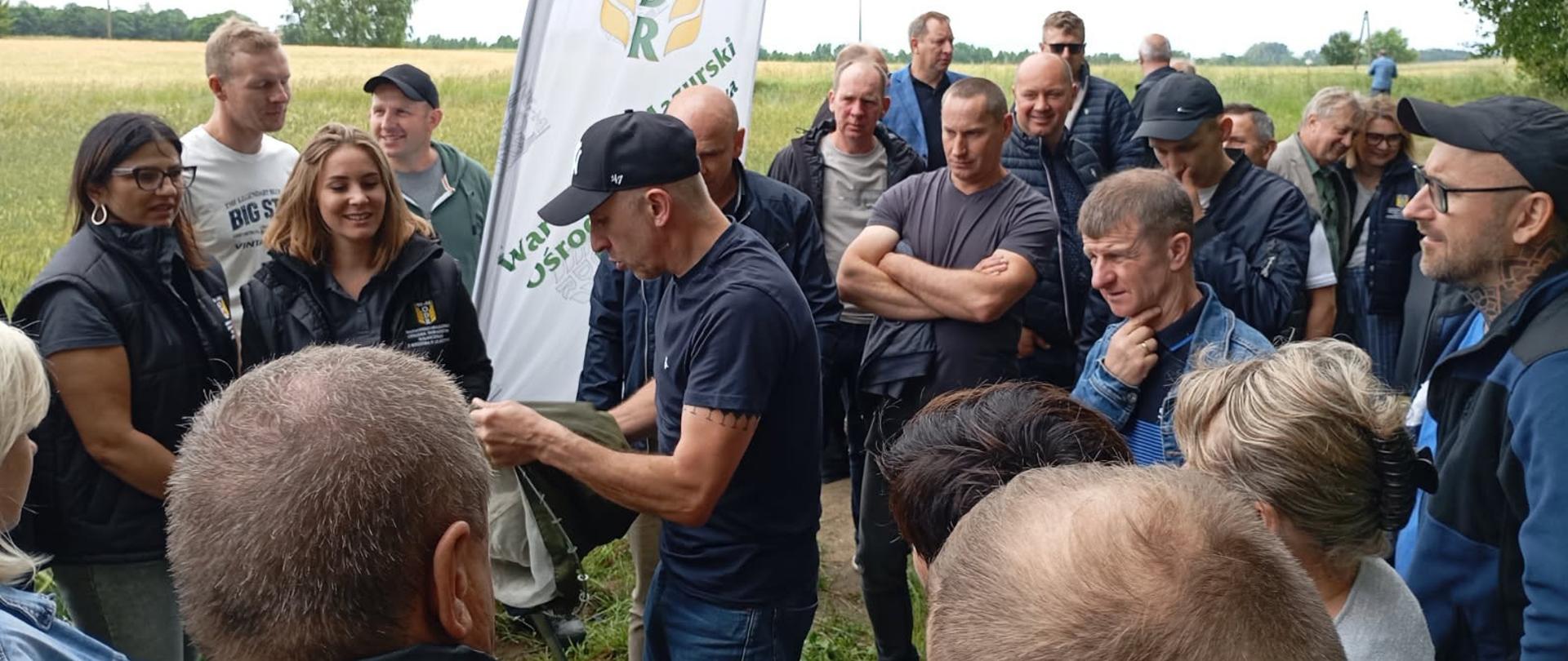 Grupa osób, która obserwuje i słucha wykładowcy na polu pszenżyta