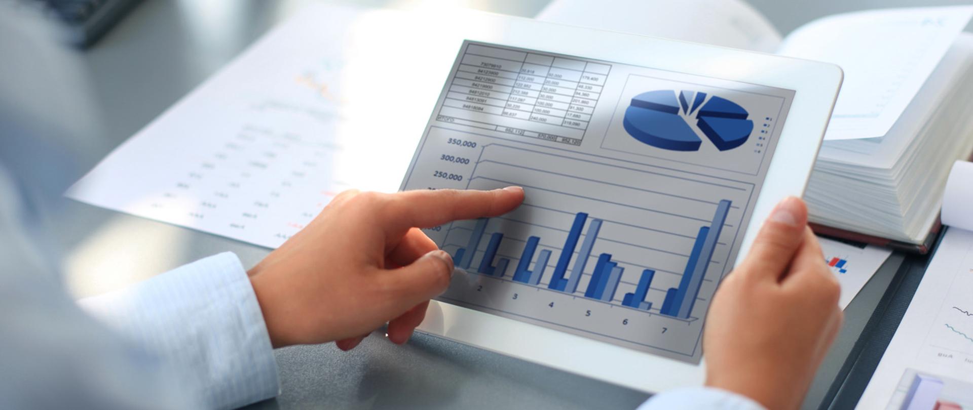 Osoba trzymająca tablet, na którym widoczny jest wykres