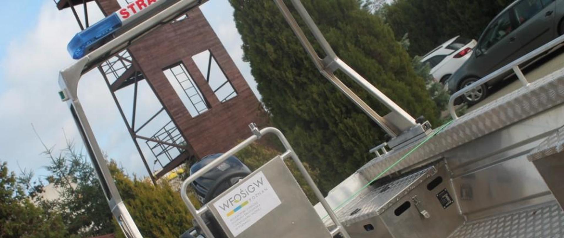 Zdjęcie przedstawia łódź ratowniczą z silnikiem wraz z wyposażeniem i przyczepą.