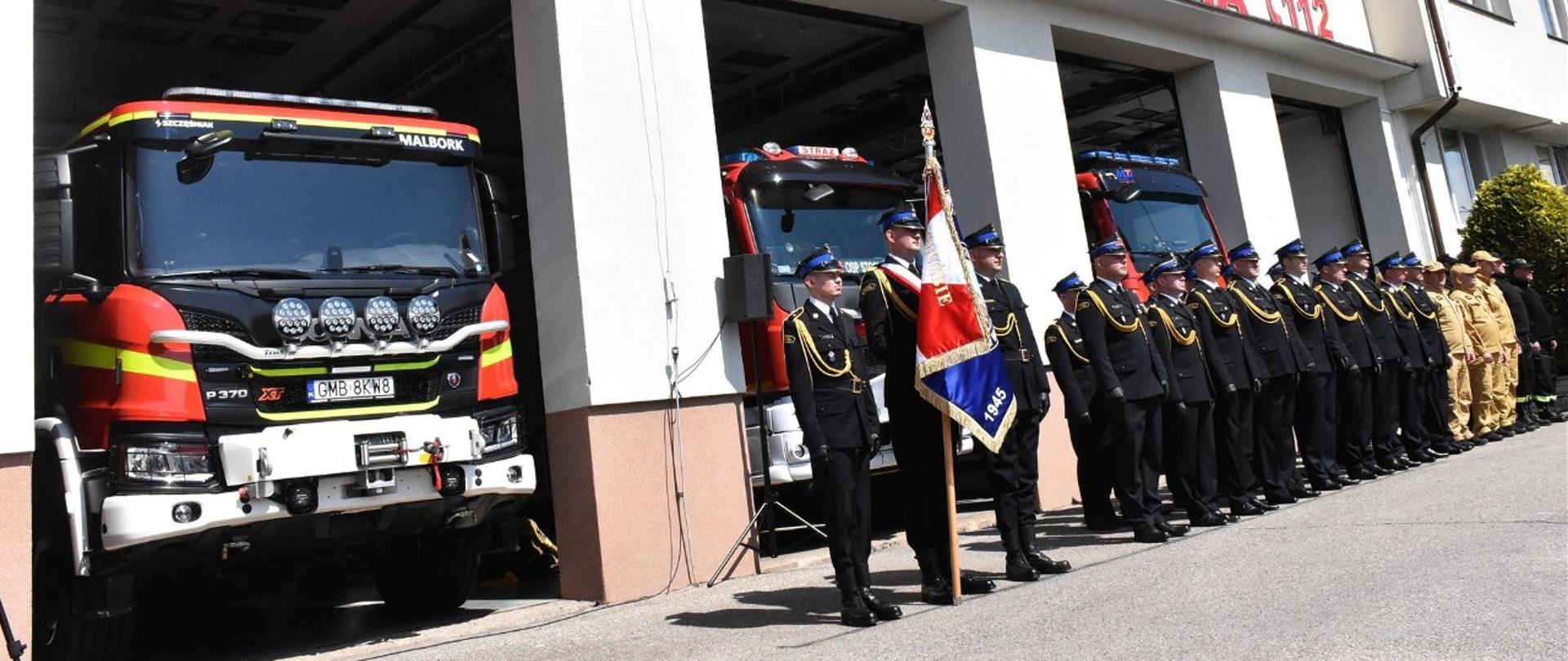Strażacy stoją w dwuszeregu na uroczystości dnia strażaka
