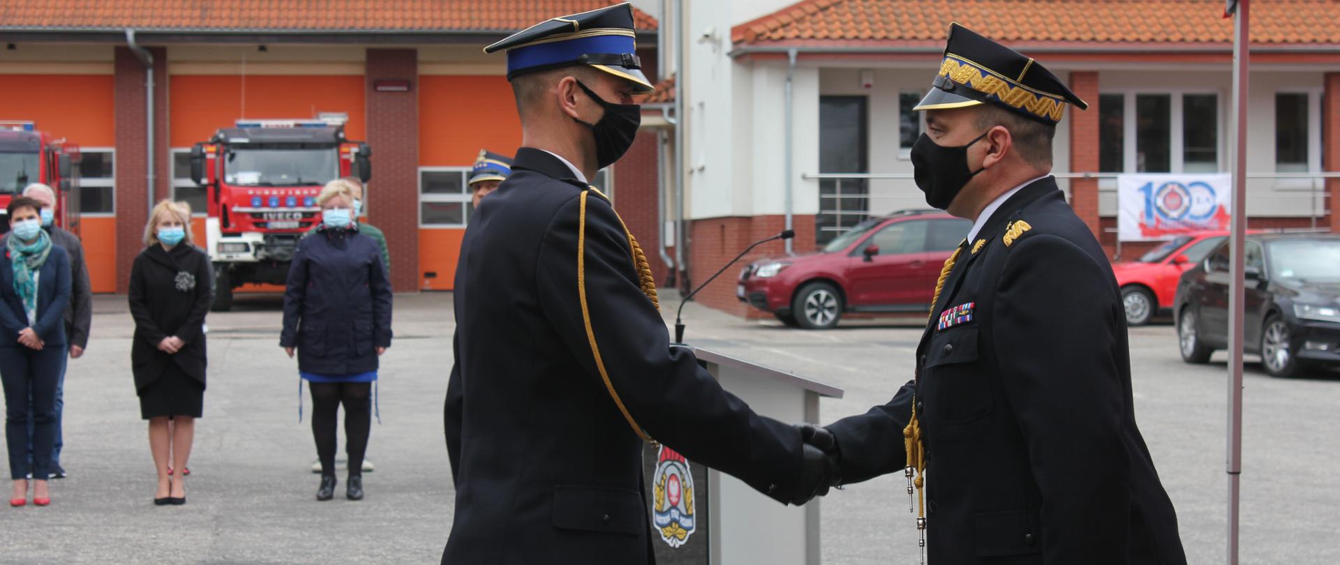 Dwóch strażaków podaje sobie ręce