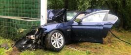 Dzień, opady deszczu. Samochód osobowy BMW wbity przodem w słup bariery dźwiękochłonnej autostrady.